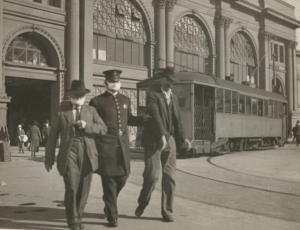 Policeman with flu mask leading two men away from the Ferry Building