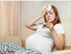 image of pregnant woman checking temperature with thermometer
